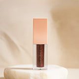 Cosmetic bottle with a pink cap and brown body on a beige background