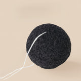 Black Konjac sponge with a white string on a beige background