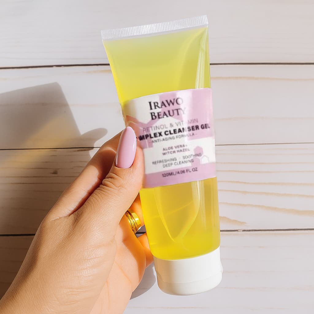 Hand holding a tube of Irawo Beauty Complex Cleanser Gel on a wooden surface