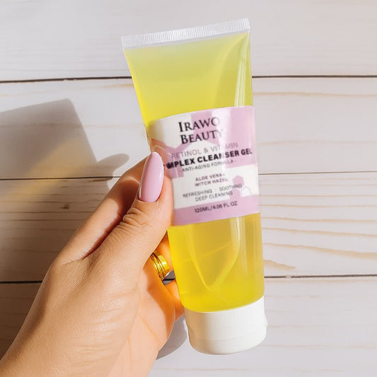 Hand holding a tube of Irawo Beauty Complex Cleanser Gel on a wooden surface