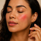 Close-up of a woman with pink blush on her cheeks against a neutral background