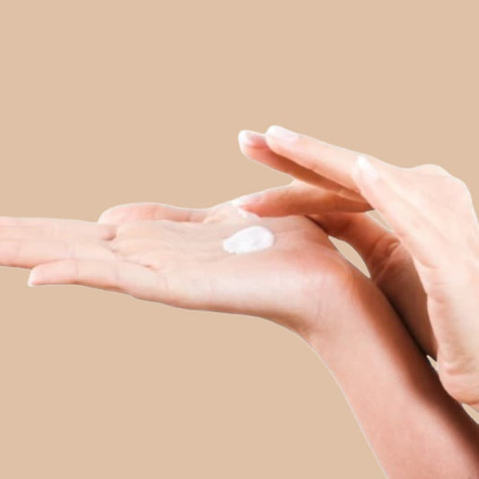 Hand applying cream on a beige background