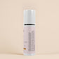 Skincare serum bottle with text on a beige background
